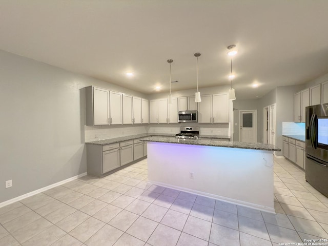 kitchen featuring dark stone countertops, light tile patterned floors, a kitchen island, pendant lighting, and appliances with stainless steel finishes