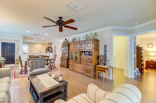 living room with light wood-type flooring, ceiling fan, and ornamental molding