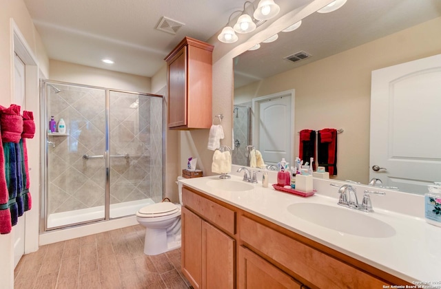 bathroom with toilet, hardwood / wood-style flooring, a shower with shower door, and vanity