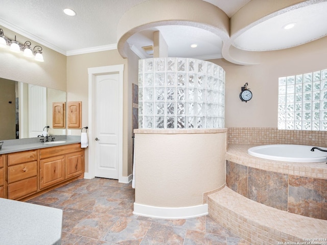 bathroom featuring tiled bath, crown molding, and vanity