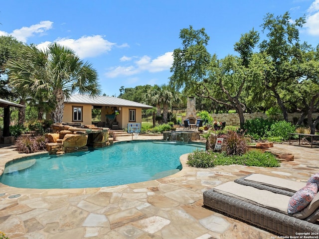 view of pool with a patio area, an outdoor fireplace, and pool water feature