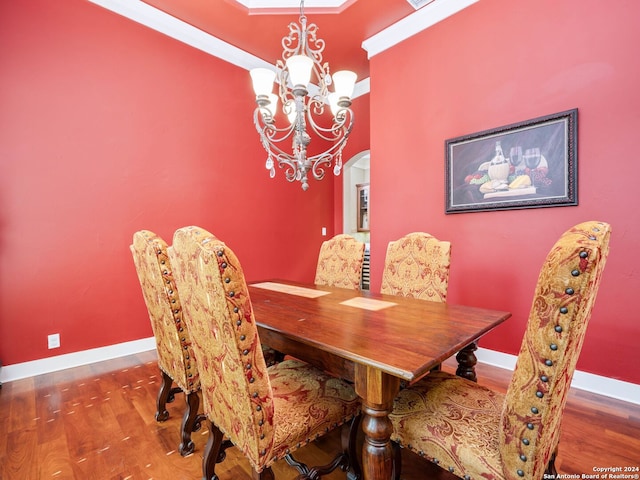 dining room with ornamental molding, an inviting chandelier, and wood-type flooring