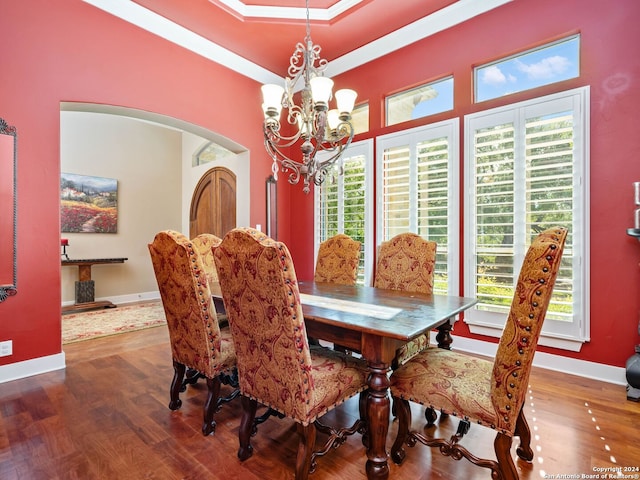 dining area with hardwood / wood-style flooring, crown molding, a chandelier, and a tray ceiling