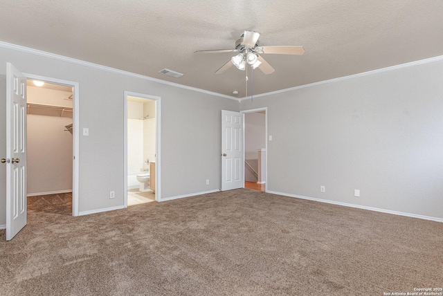 unfurnished bedroom featuring a spacious closet, a closet, connected bathroom, crown molding, and ceiling fan