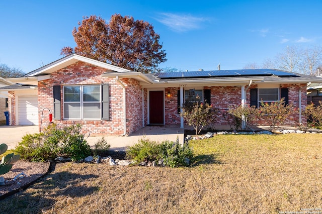 ranch-style home featuring covered porch, solar panels, a front lawn, and a garage