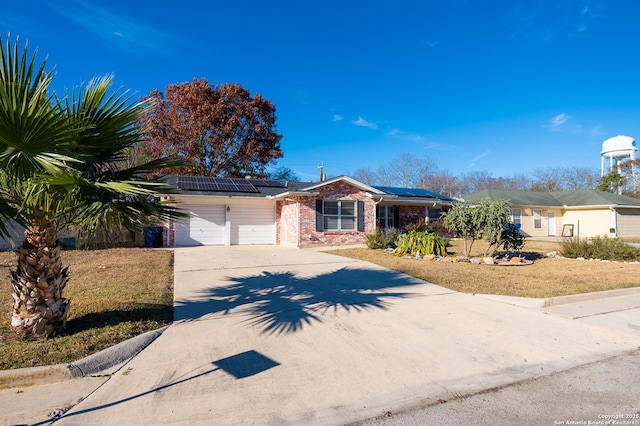 ranch-style house featuring solar panels, a front yard, and a garage