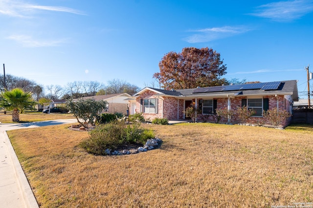 ranch-style home featuring solar panels and a front yard