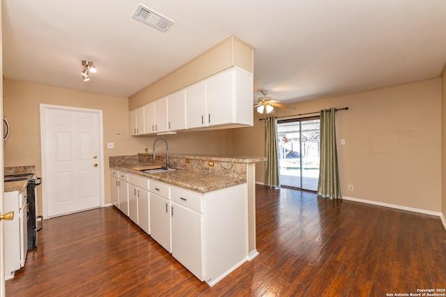 kitchen with kitchen peninsula, electric range, white cabinetry, and sink