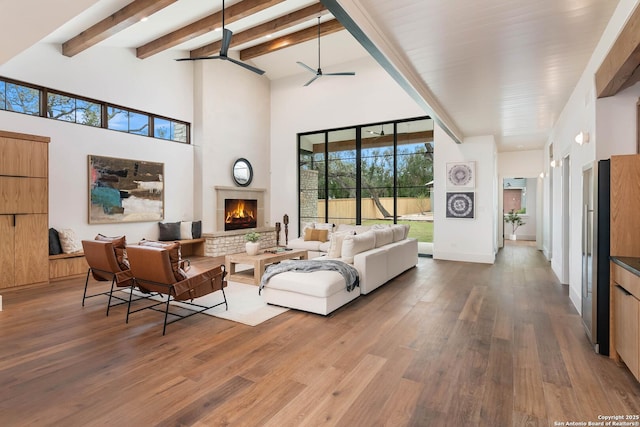 living room featuring ceiling fan, hardwood / wood-style floors, beam ceiling, and a high ceiling