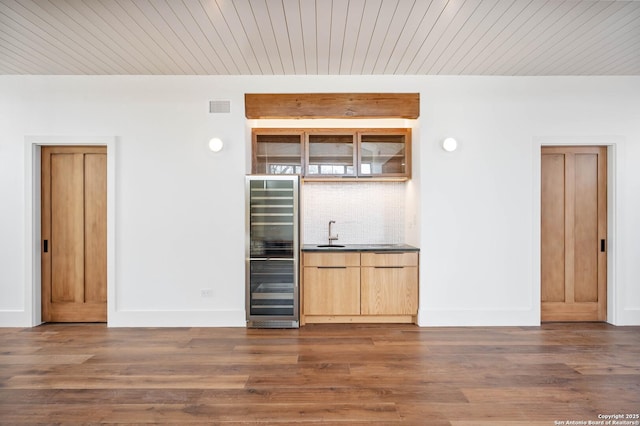 bar featuring sink, beverage cooler, decorative backsplash, and dark hardwood / wood-style floors