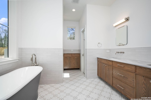 bathroom featuring tile walls, a tub to relax in, and vanity