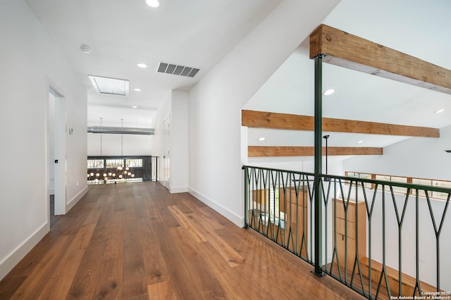 corridor featuring hardwood / wood-style floors, lofted ceiling with beams, and a chandelier