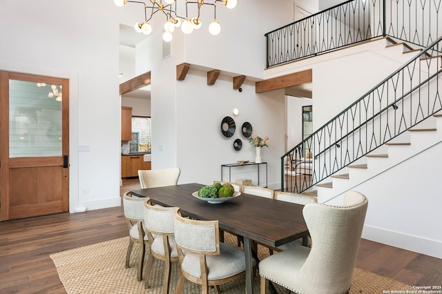 dining area featuring a high ceiling, a notable chandelier, and dark hardwood / wood-style flooring