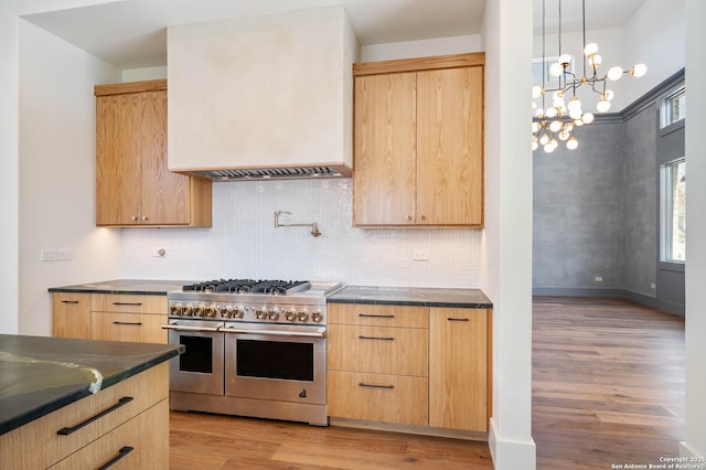 kitchen featuring a notable chandelier, light wood-type flooring, range with two ovens, and light brown cabinets