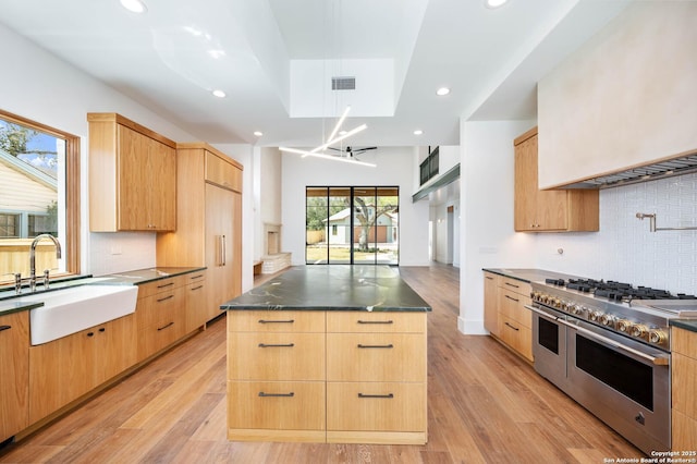 kitchen featuring high quality appliances, light brown cabinetry, a kitchen island, and sink