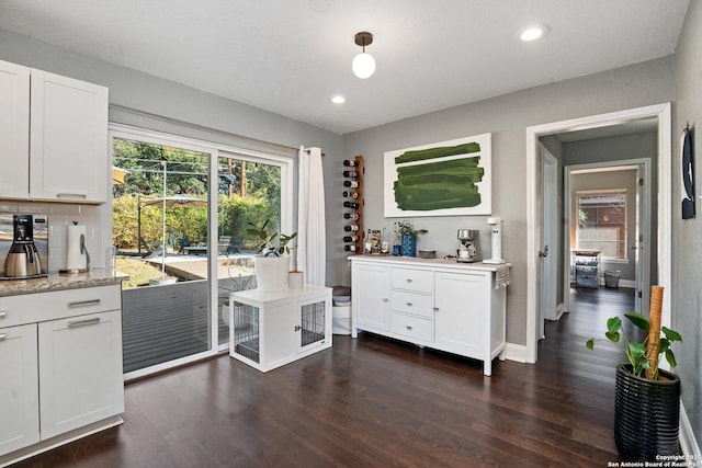 interior space with white cabinets, dark wood-type flooring, light stone counters, and tasteful backsplash