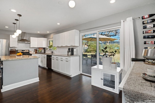 kitchen featuring white cabinets, wall chimney range hood, pendant lighting, and stainless steel appliances