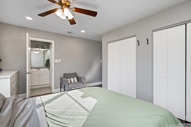 bedroom with sink, connected bathroom, multiple closets, and ceiling fan