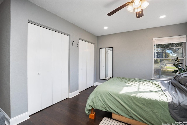 bedroom featuring ceiling fan, dark hardwood / wood-style flooring, and two closets