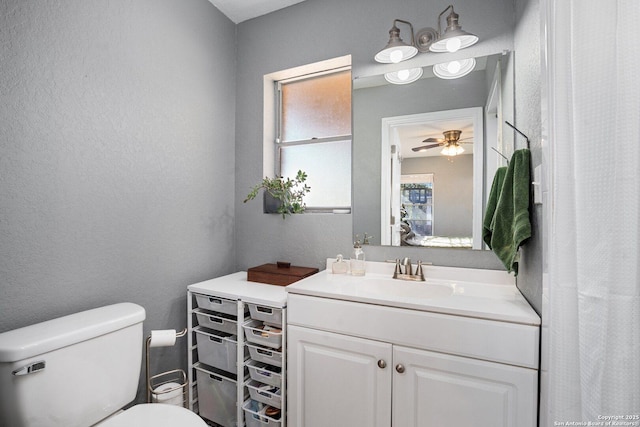 bathroom featuring toilet, vanity, and ceiling fan