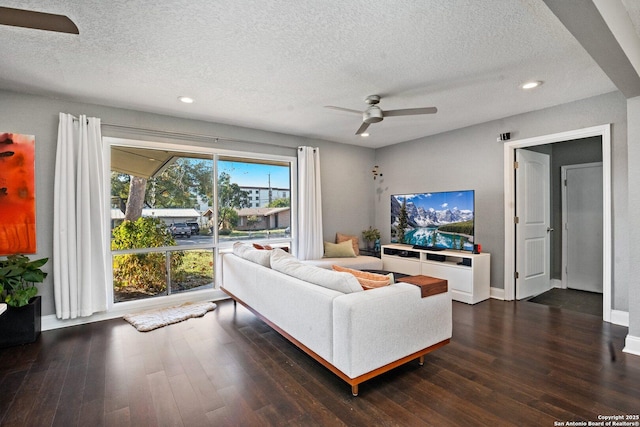 living room with a textured ceiling, ceiling fan, and dark hardwood / wood-style flooring