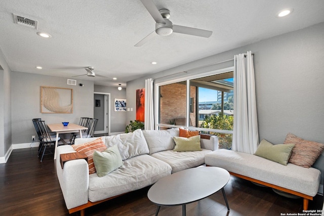 living room featuring a textured ceiling, ceiling fan, and dark wood-type flooring