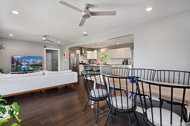 dining area featuring a textured ceiling, ceiling fan, and dark wood-type flooring