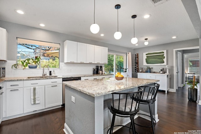 kitchen featuring sink, a kitchen island, and white cabinetry