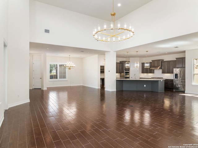 unfurnished living room with a notable chandelier and high vaulted ceiling