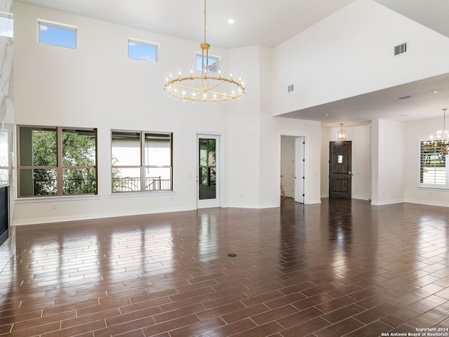 unfurnished living room with a towering ceiling and a notable chandelier