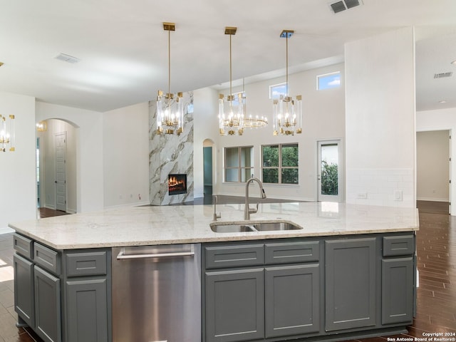 kitchen featuring sink, dishwasher, light stone counters, gray cabinets, and a high end fireplace