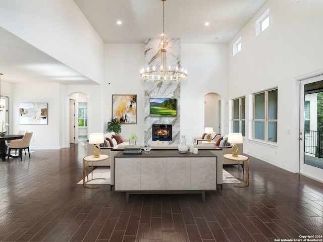 living room featuring a towering ceiling, a premium fireplace, and an inviting chandelier