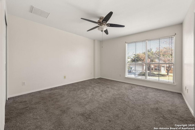 empty room with ceiling fan and dark colored carpet