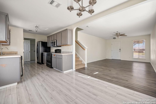 kitchen with appliances with stainless steel finishes, light hardwood / wood-style flooring, gray cabinets, and sink