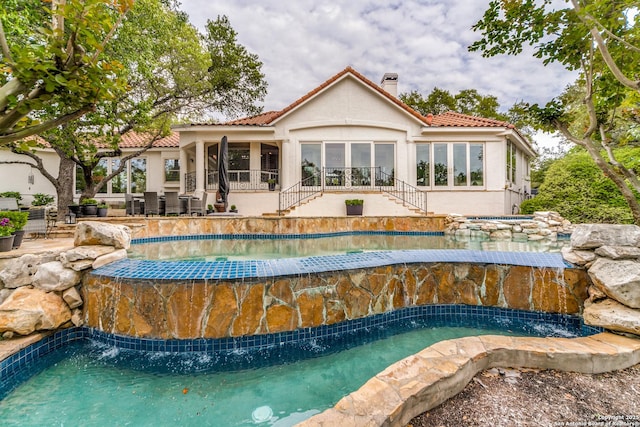 view of swimming pool featuring a hot tub, pool water feature, and a patio area