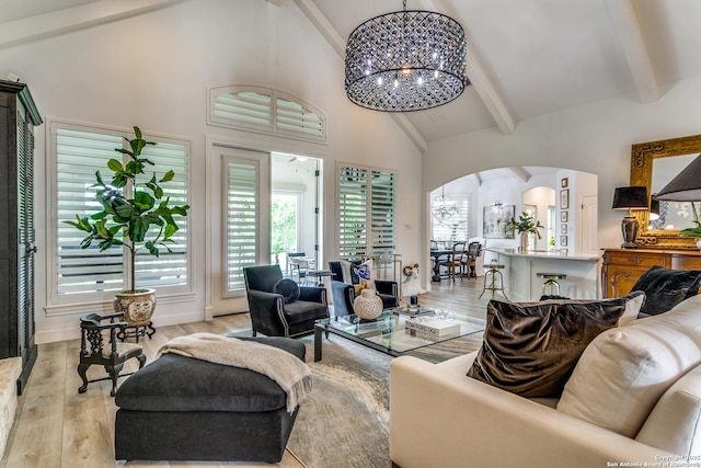 living room featuring beamed ceiling, high vaulted ceiling, light wood-type flooring, and a chandelier