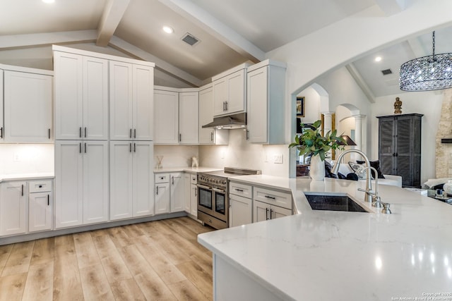 kitchen with sink, hanging light fixtures, vaulted ceiling with beams, and high end stainless steel range oven