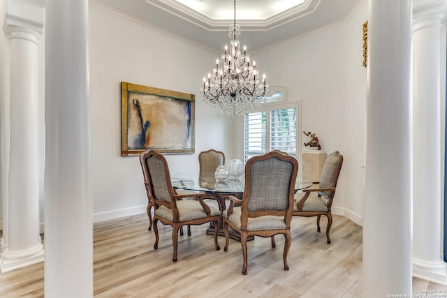 dining space featuring a raised ceiling, decorative columns, light wood-type flooring, and crown molding