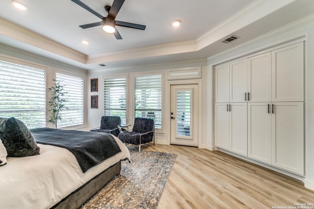 bedroom featuring a raised ceiling, light wood-type flooring, crown molding, ceiling fan, and access to exterior