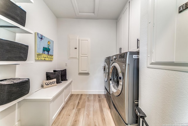 laundry area with electric panel, washing machine and dryer, light wood-type flooring, and cabinets