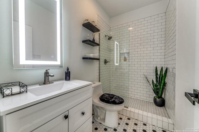 bathroom with toilet, tile patterned flooring, a tile shower, and vanity