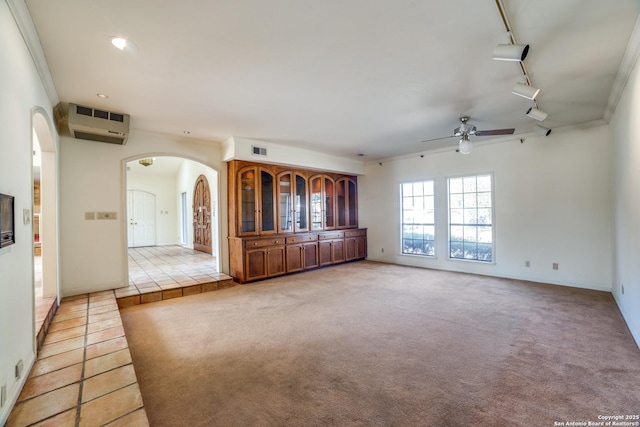 unfurnished living room featuring rail lighting, light carpet, ornamental molding, and ceiling fan