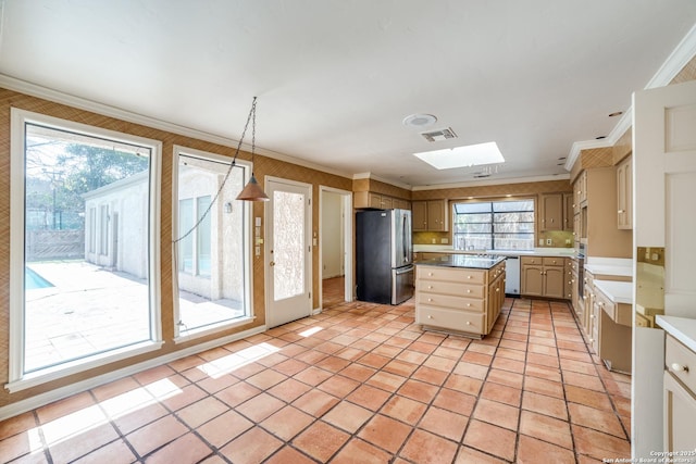 kitchen with a center island, decorative light fixtures, a skylight, crown molding, and appliances with stainless steel finishes