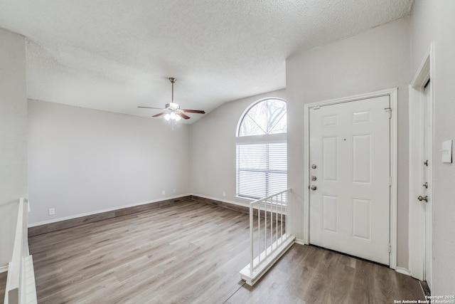 foyer with lofted ceiling, a textured ceiling, hardwood / wood-style floors, and ceiling fan