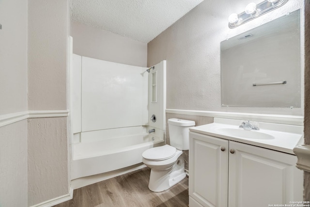 full bathroom featuring hardwood / wood-style floors, toilet, vanity, a textured ceiling, and shower / bathtub combination