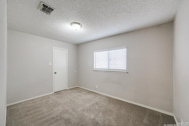 empty room with a textured ceiling and light carpet