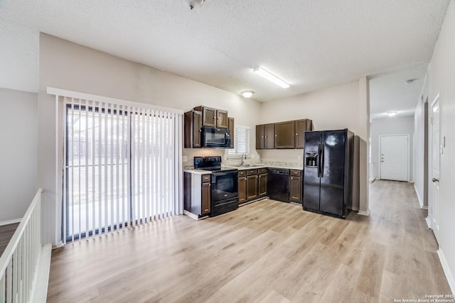 kitchen with sink, a textured ceiling, light hardwood / wood-style flooring, a healthy amount of sunlight, and black appliances