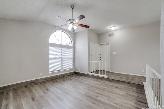 spare room featuring light hardwood / wood-style floors, a textured ceiling, ceiling fan, and vaulted ceiling