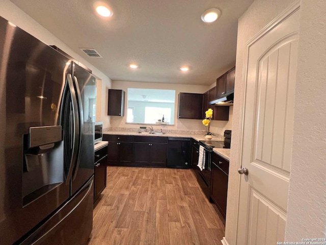 kitchen with black appliances, light hardwood / wood-style flooring, sink, and dark brown cabinetry