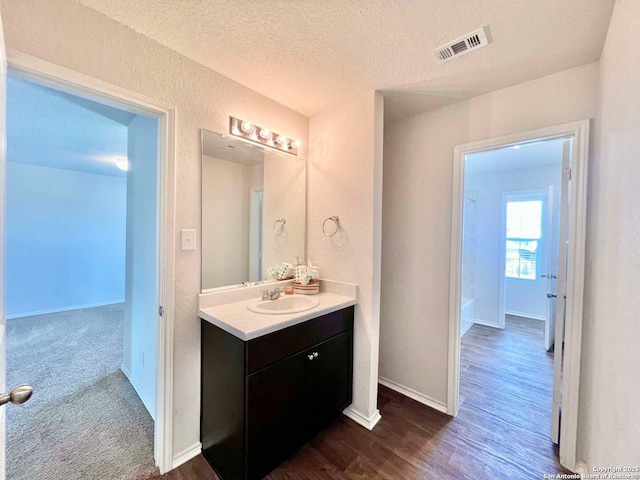 bathroom with a textured ceiling, wood-type flooring, and vanity